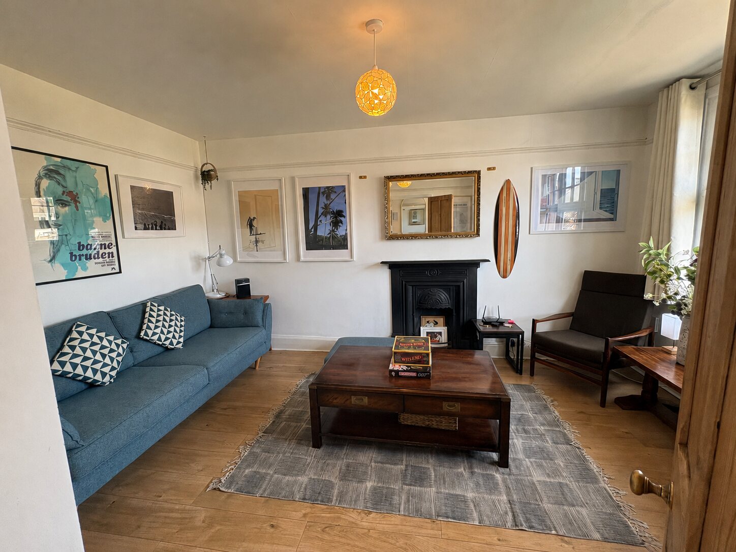 Bright sitting room with blue sofa, original fireplace and surfboard at Bude Surf Shack holiday home in Bude